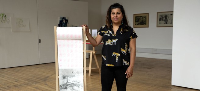 A portrait of Erika Servin Gonzalez holding up one of her prints