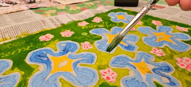 A work in progress. A piece of brightly coloured batik work with blue flowers by Louise Underwood.